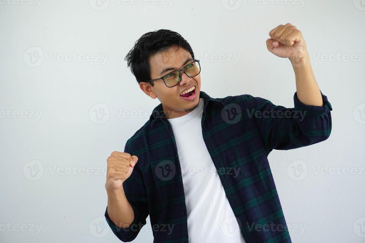 joven asiático hombre gritando éxito con su puño apretado aislado en blanco antecedentes foto