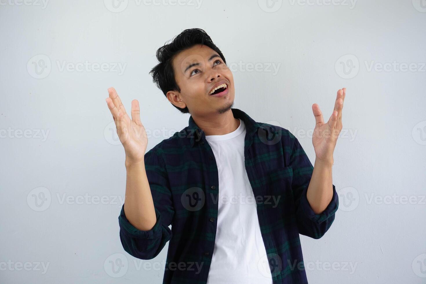 young asian man showing cheerful face expression and looking up with both hands open isolated on white background photo
