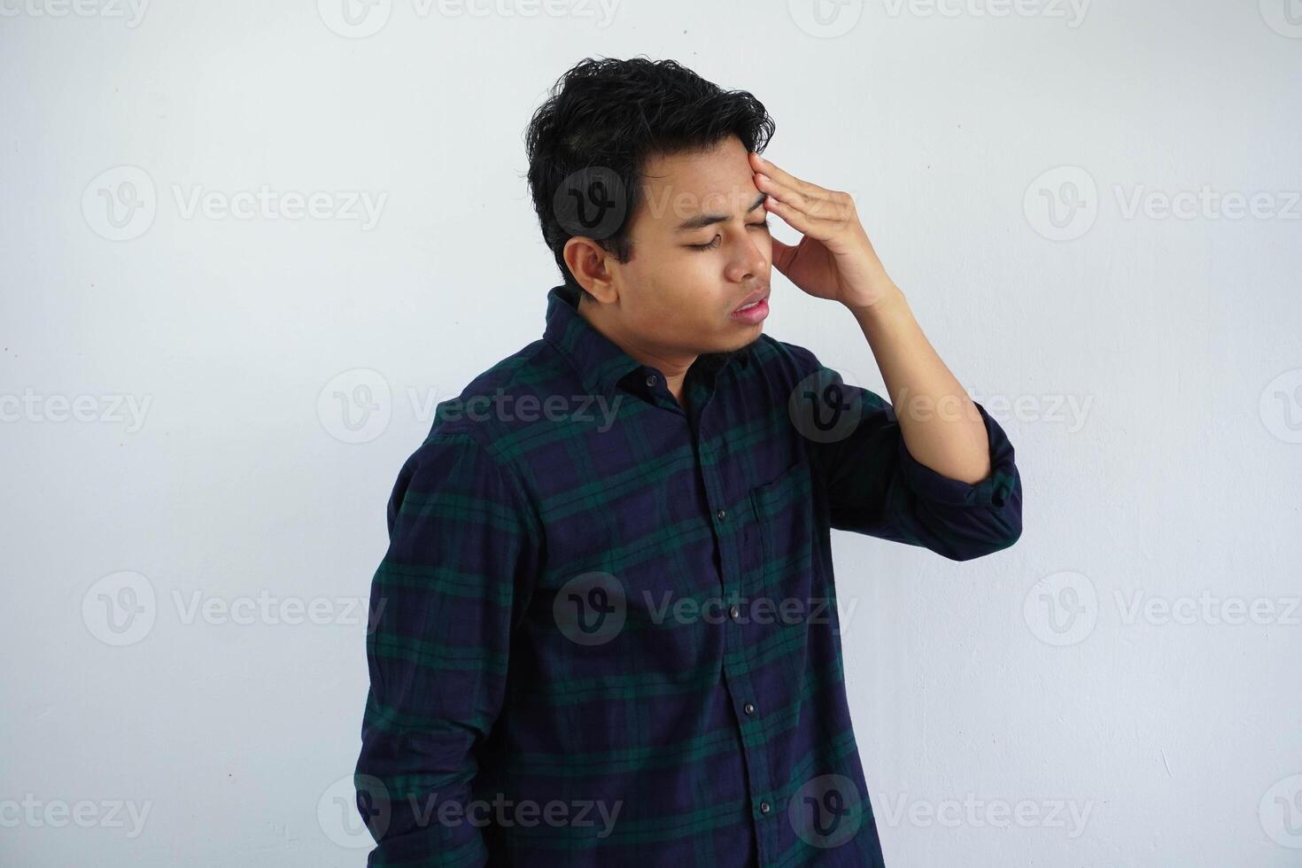 dizzy young asian man showing gesture with hand touching forehead isolated on white background. photo