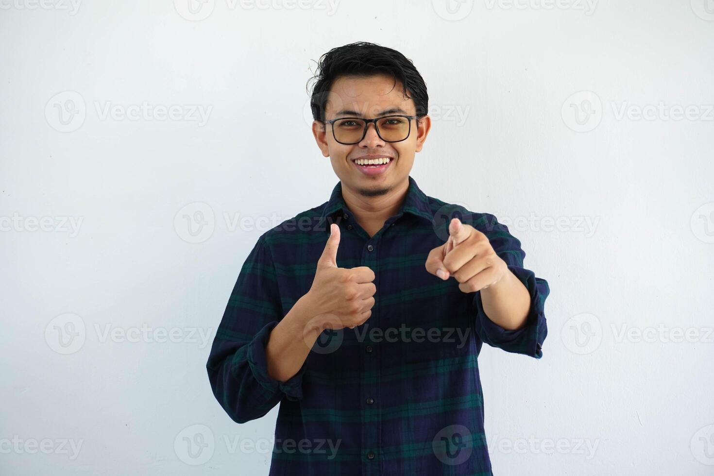 smiling young asian man pointing forward while giving thumb up isolated on white background. photo