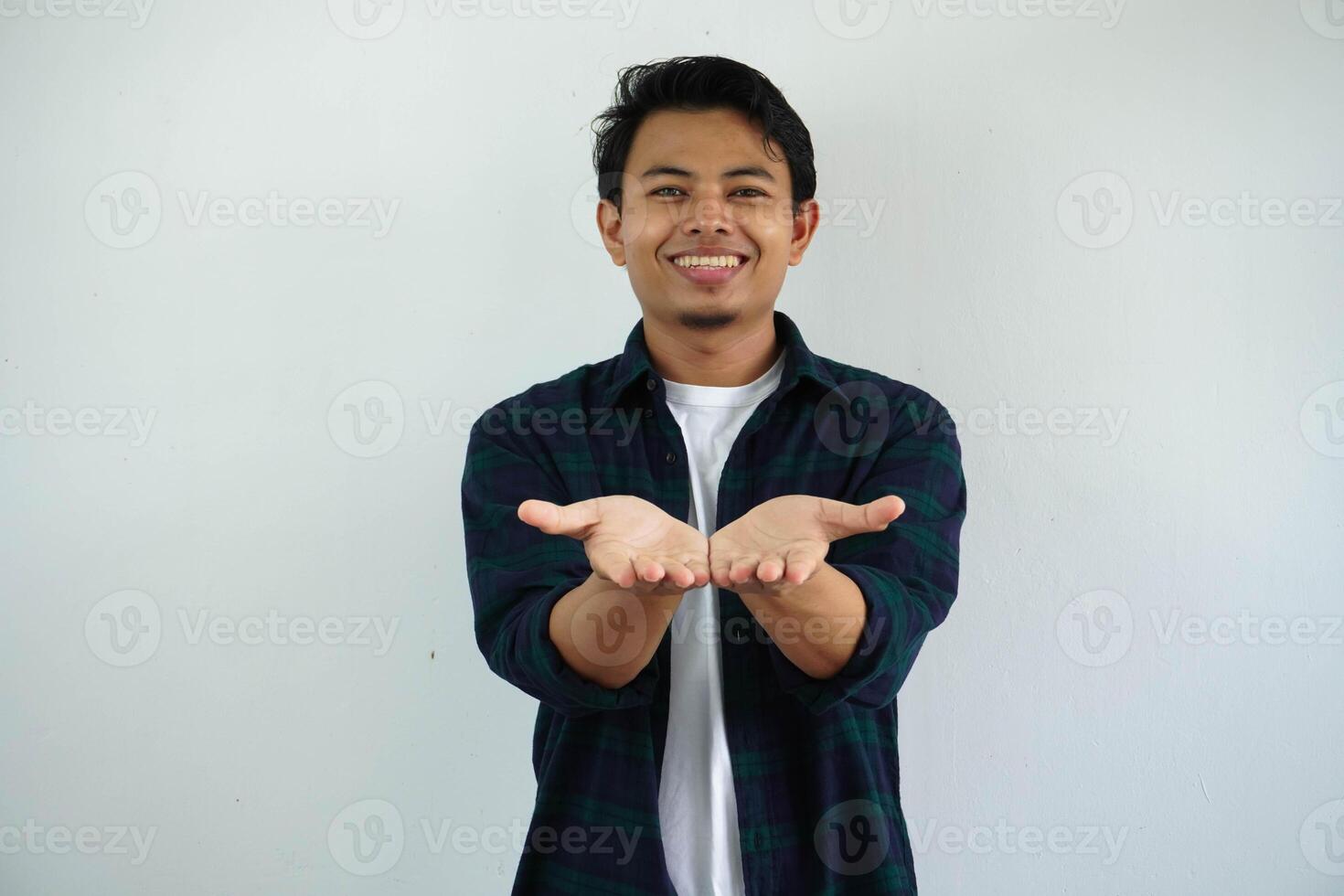 joven asiático hombre sonriente contento con ambos mano haciendo dando alguna cosa actitud aislado en blanco antecedentes. foto