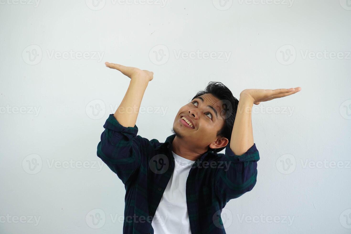 young asian man acting like he's holding up something heavy, but it's just empty copy space isolated on white background. shocked face photo