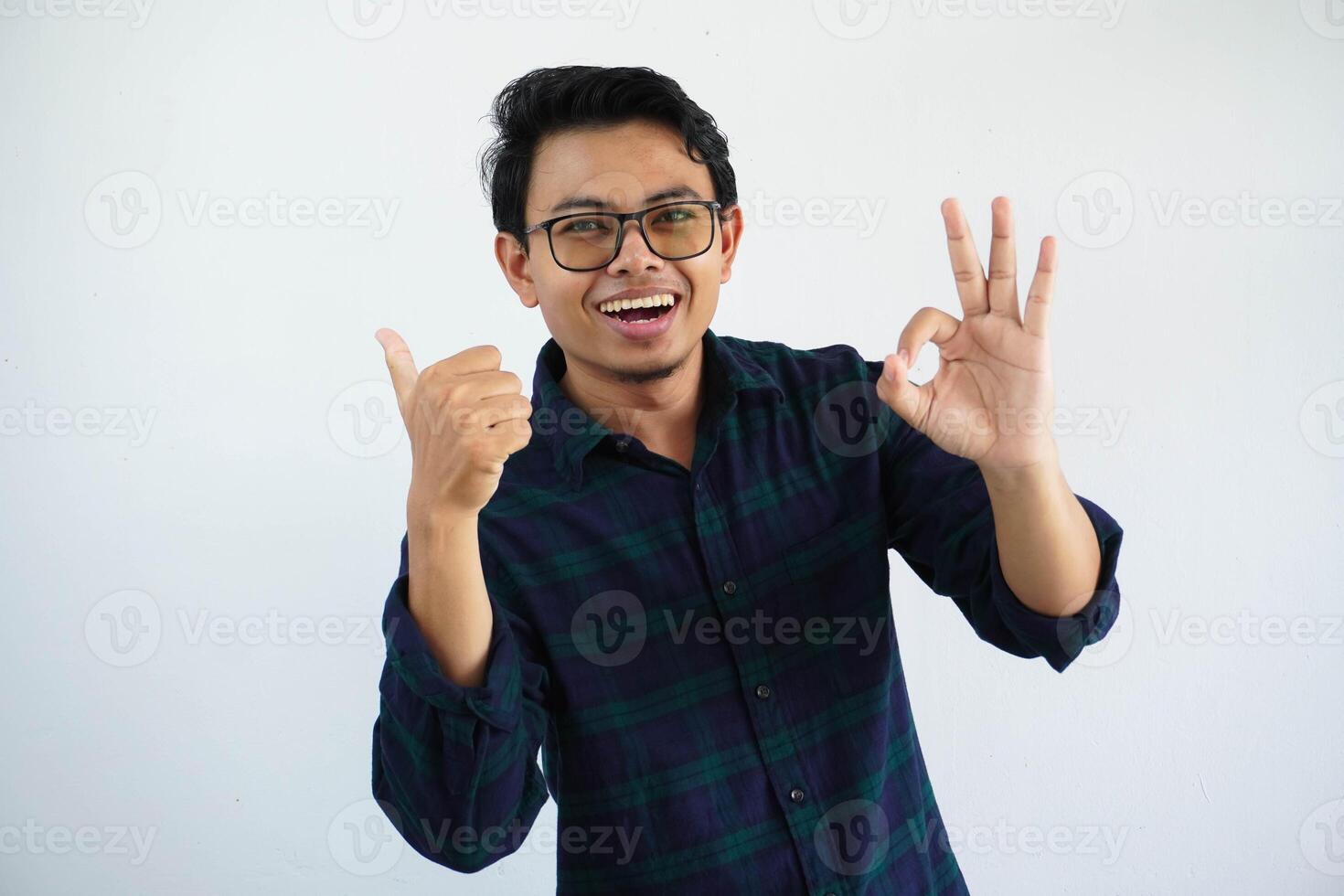 young asian man smiling happy while pointing behind and give OK sign isolated on white background. photo