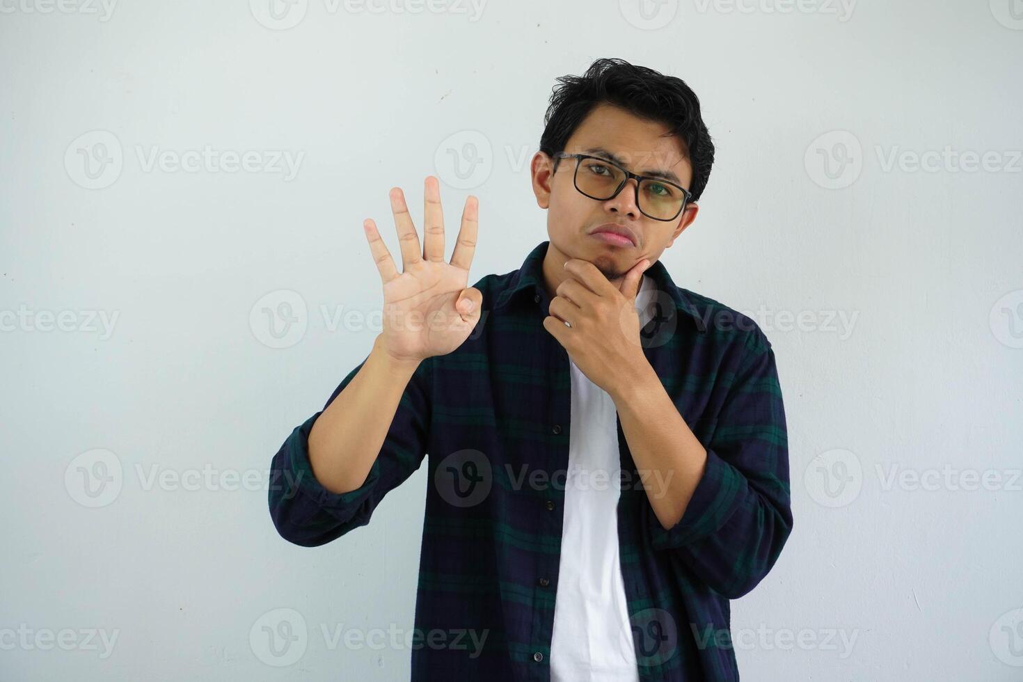 young asian man showing curious face expression while giving four fingers sign isolated on white background photo