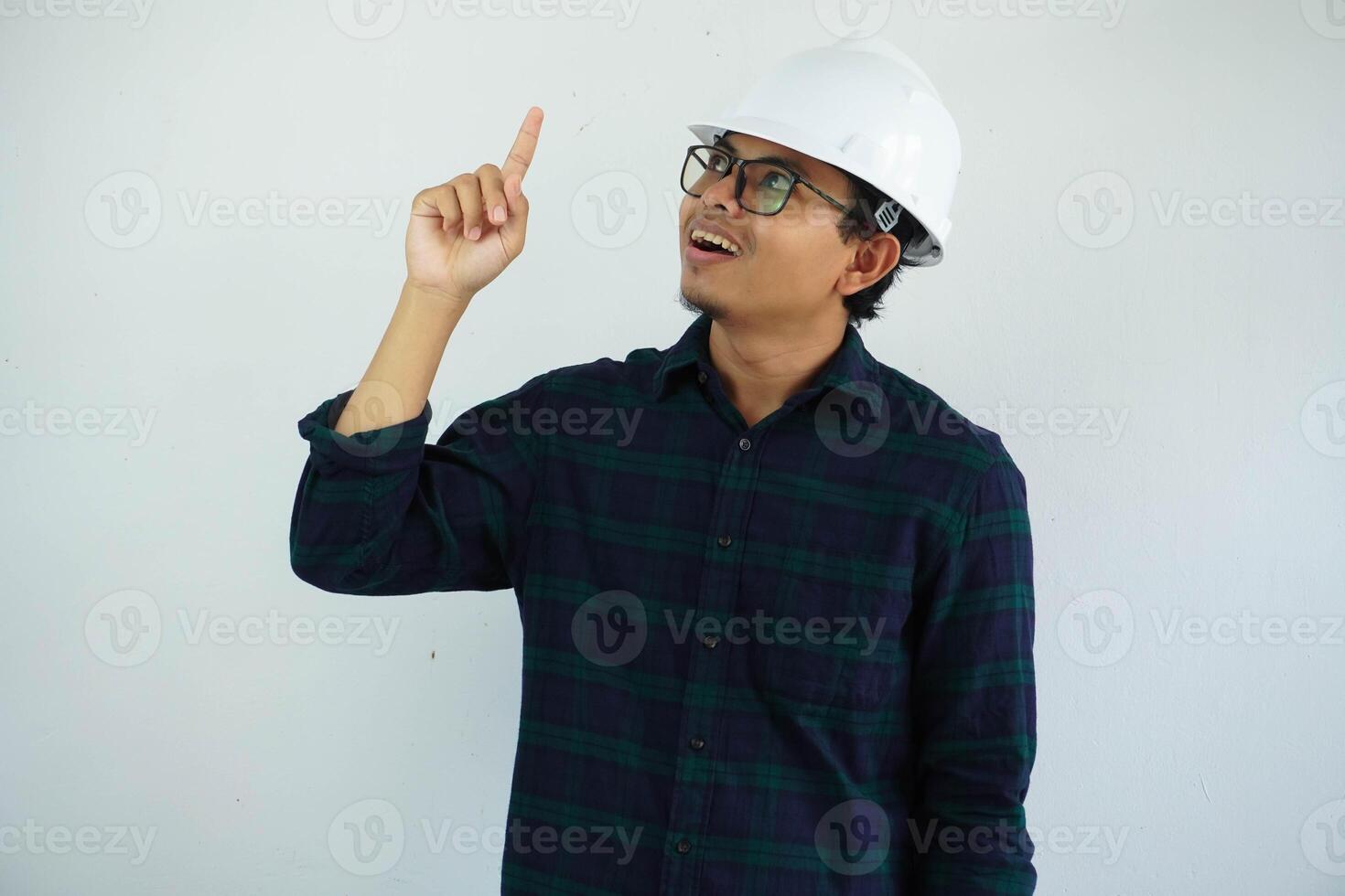 emocionado joven asiático arquitecto hombre vistiendo blanco difícil sombrero la seguridad casco con dedo señalando arriba aislado en blanco antecedentes foto