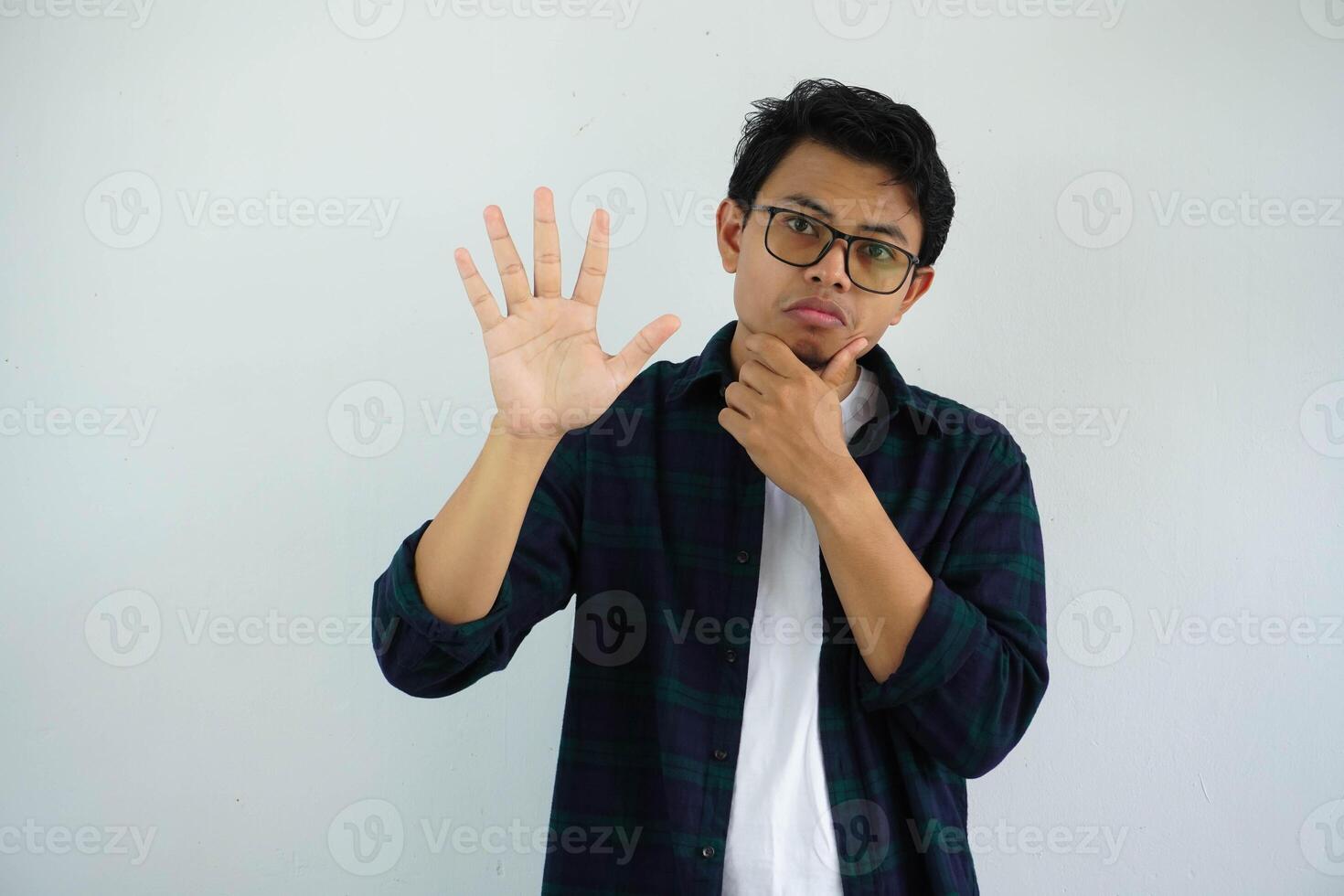 young asian man showing curious face expression while giving five fingers sign isolated on white background photo