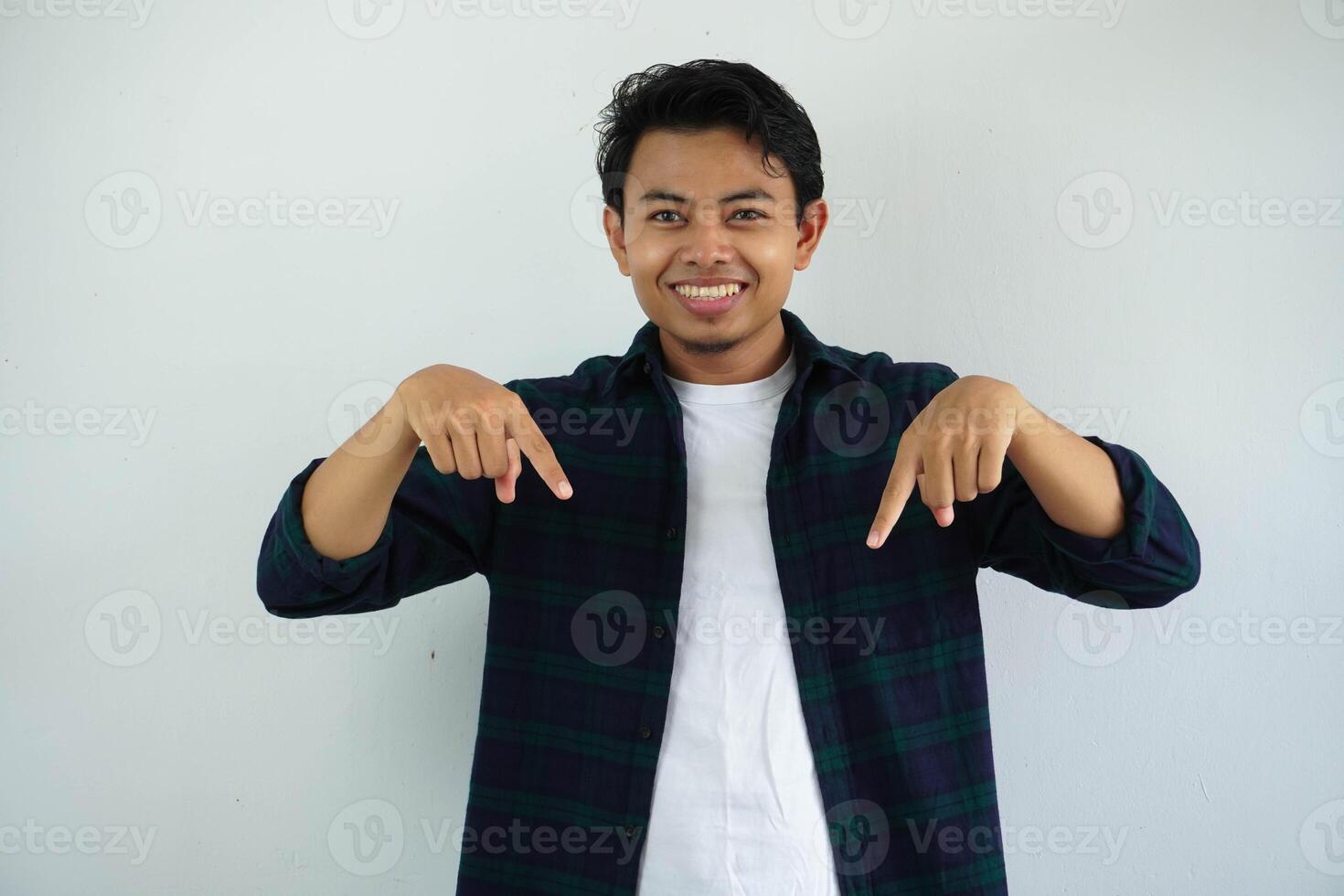 sonriente joven asiático hombre demostración contento cara expresión mientras señalando abajo aislado en blanco antecedentes foto