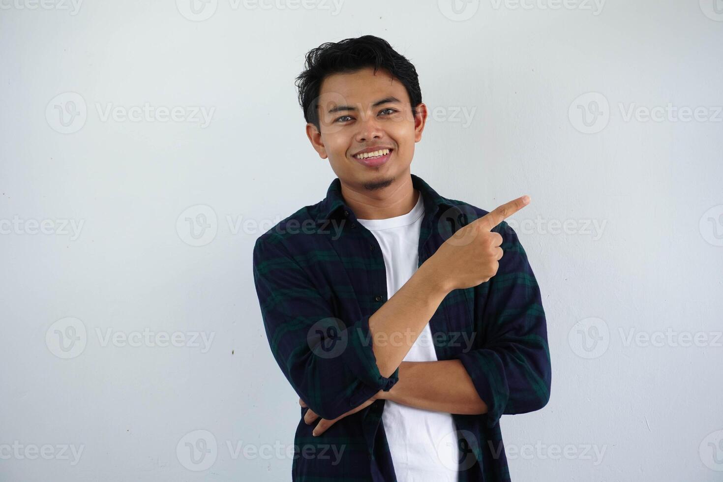 young asian man smiling happy with his right hand pointing to the left side isolated on white background photo