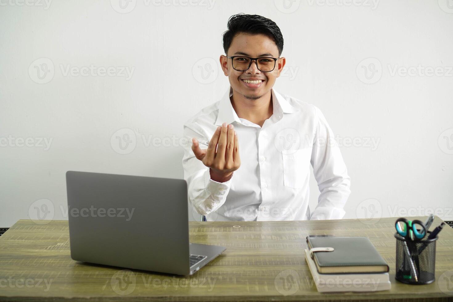 young asian businessman in a workplace inviting to come with hand. happy that you came, wear white shirt with glasses isolated photo