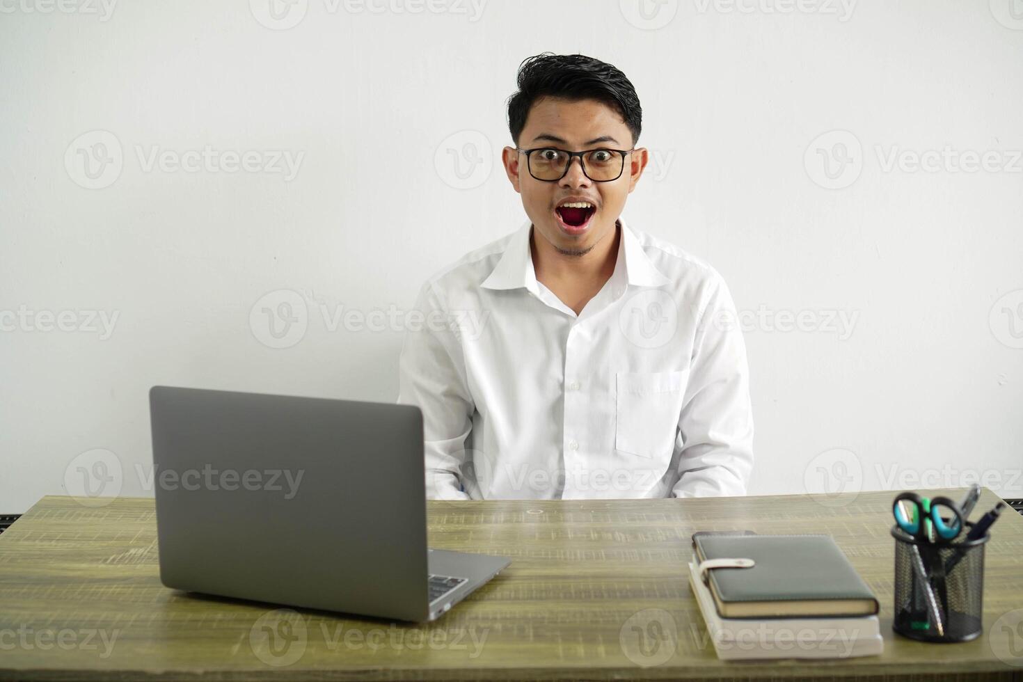 young asian businessman in a workplace with surprise facial expression, wearing white shirt with glasses isolated photo