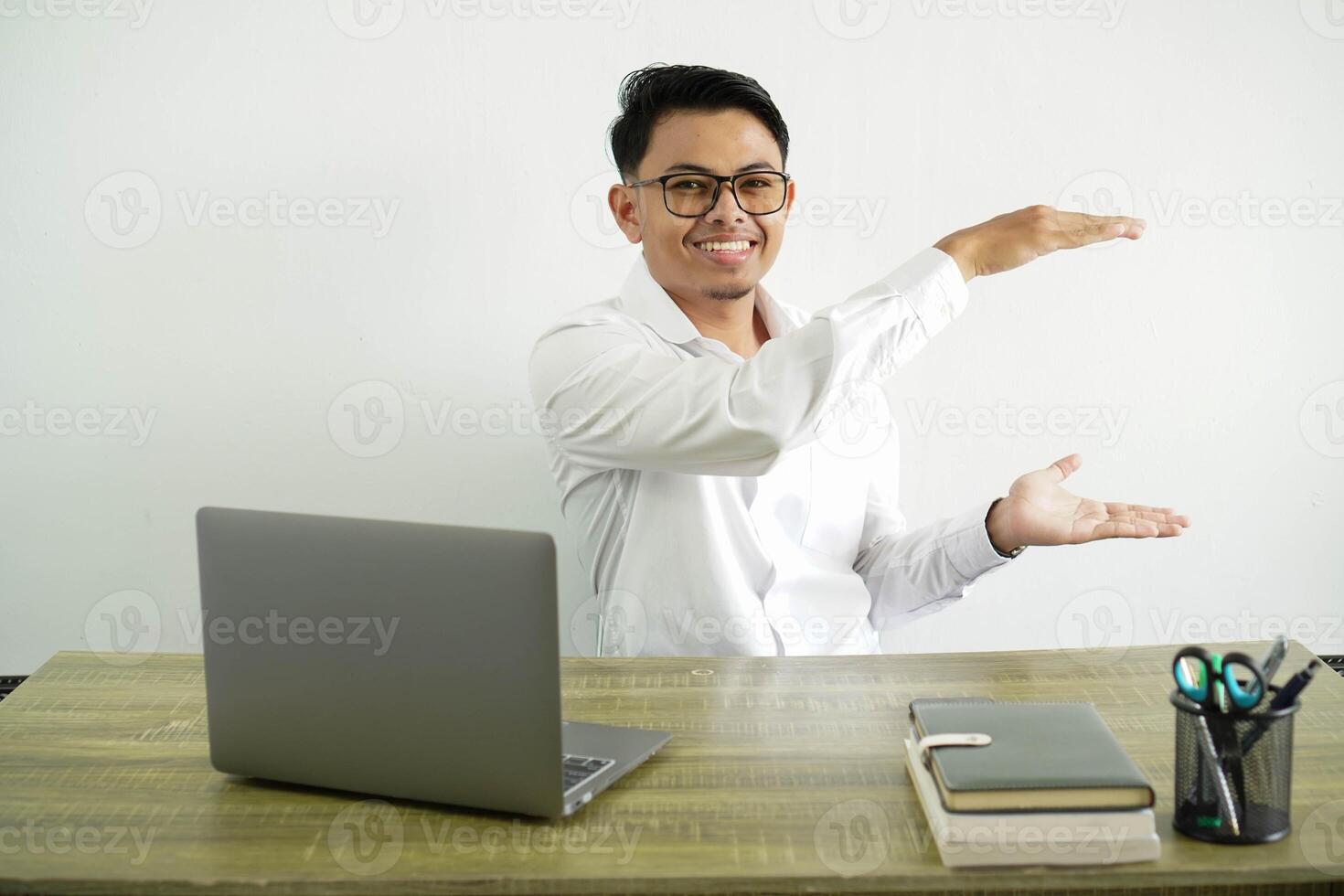 young asian businessman in a workplace holding copy space to insert an ad, wearing white shirt with glasses isolated photo