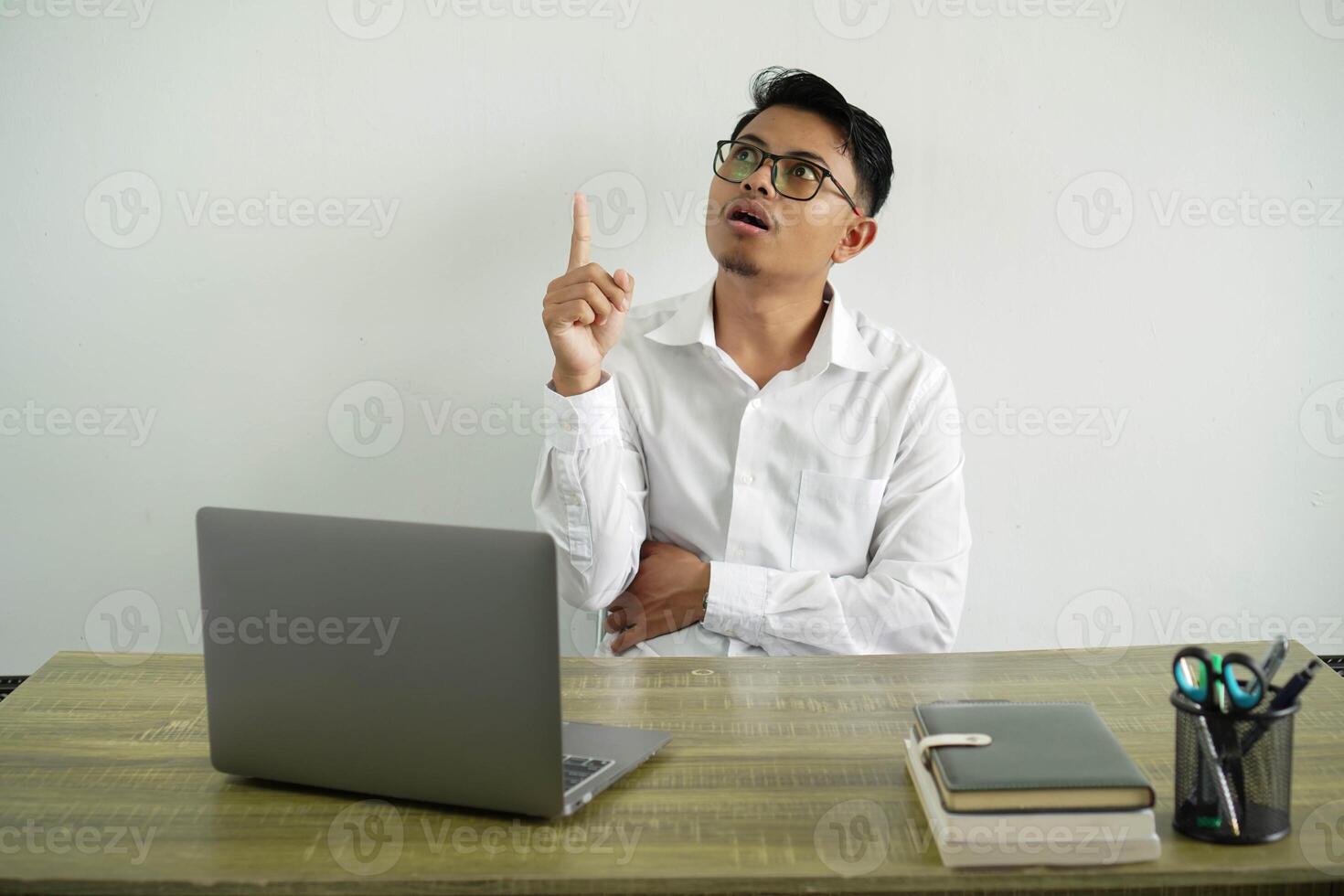 young asian businessman in a workplace thinking an idea pointing the finger up, wearing white shirt with glasses isolated photo