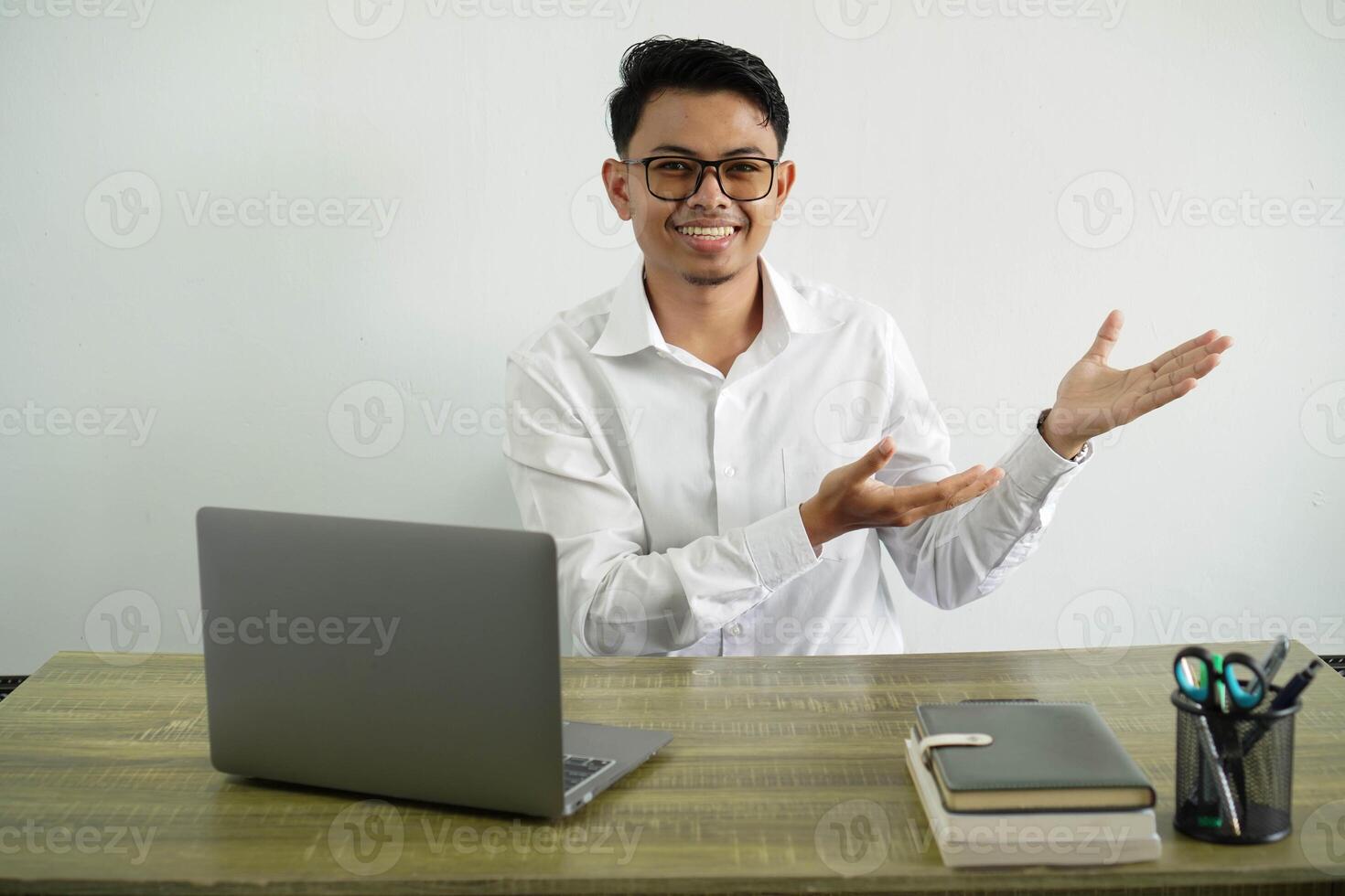 young asian businessman in a workplace extending hands to the side for inviting to come, wear white shirt with glasses isolated photo