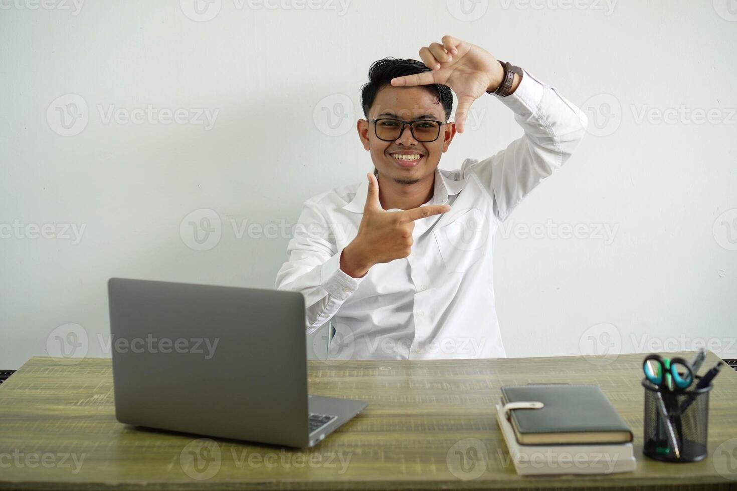 young asian businessman in a workplace focusing face. framing symbol, wearing white shirt with glasses isolated photo