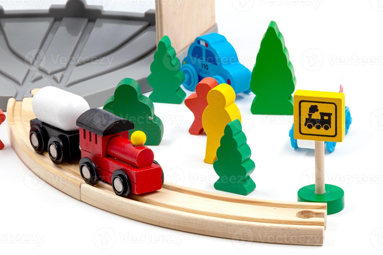 Children's toy train with two cars on a wooden railroad. Trees and green Christmas trees with people and signs complete the toy world. For children's play. White background. High quality photo. photo