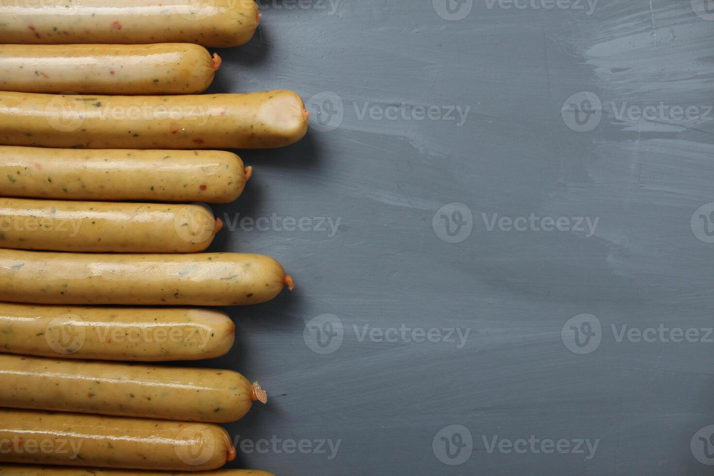Chicken sausages with herbs lie next to each other on a gray background with space for copyspace text. Preparation for a barbecue picnic photo
