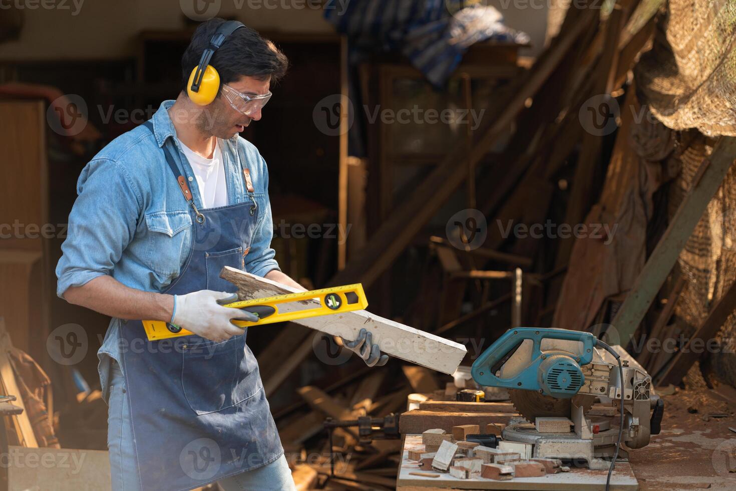 Portrait of a carpenter holding a spirit level in his workshop. photo