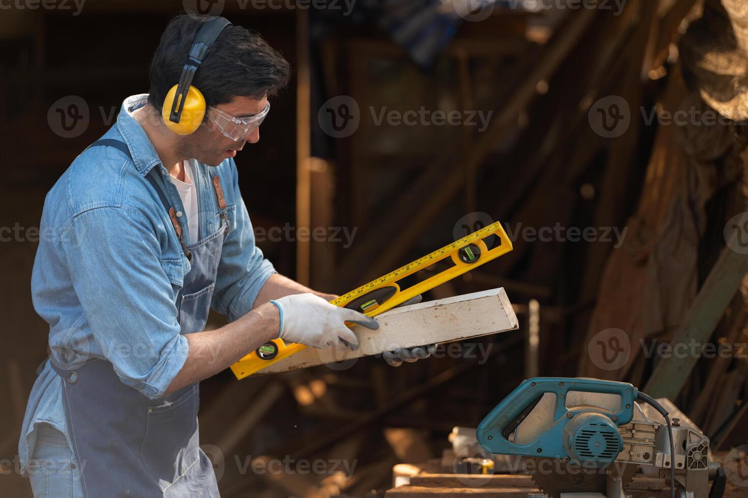 Portrait of a carpenter holding a spirit level in his workshop. photo