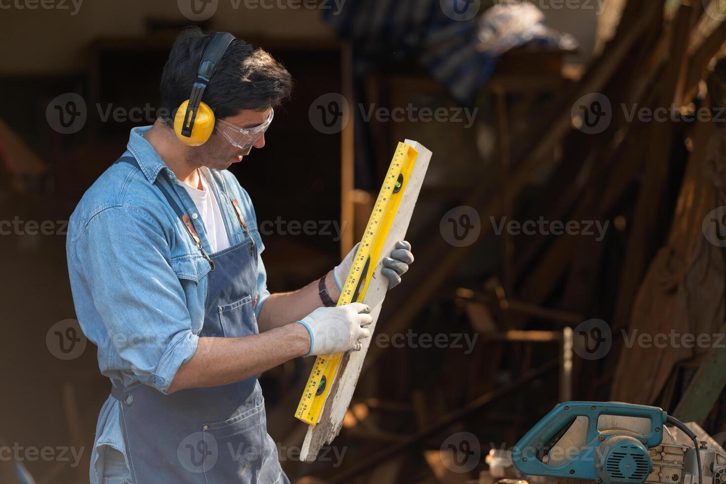 Portrait of a carpenter holding a spirit level in his workshop. photo