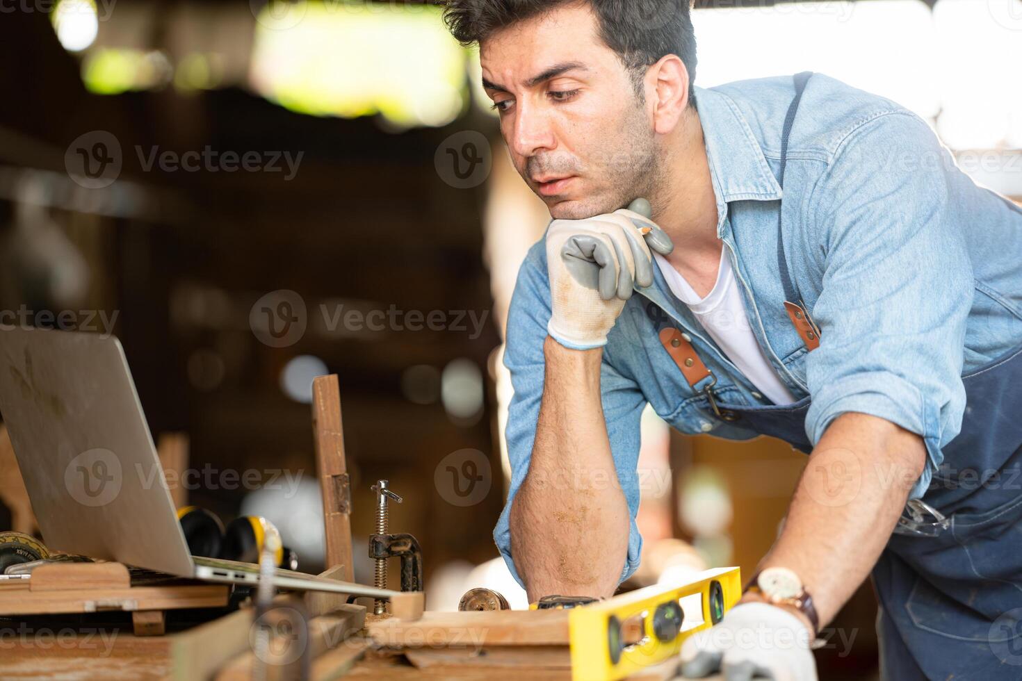 Carpenter working on laptop in his workshop at a woodworking factory photo