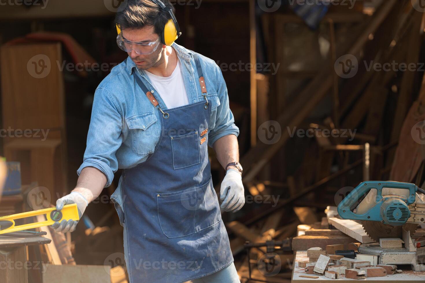 Portrait of a carpenter holding a spirit level in his workshop. photo