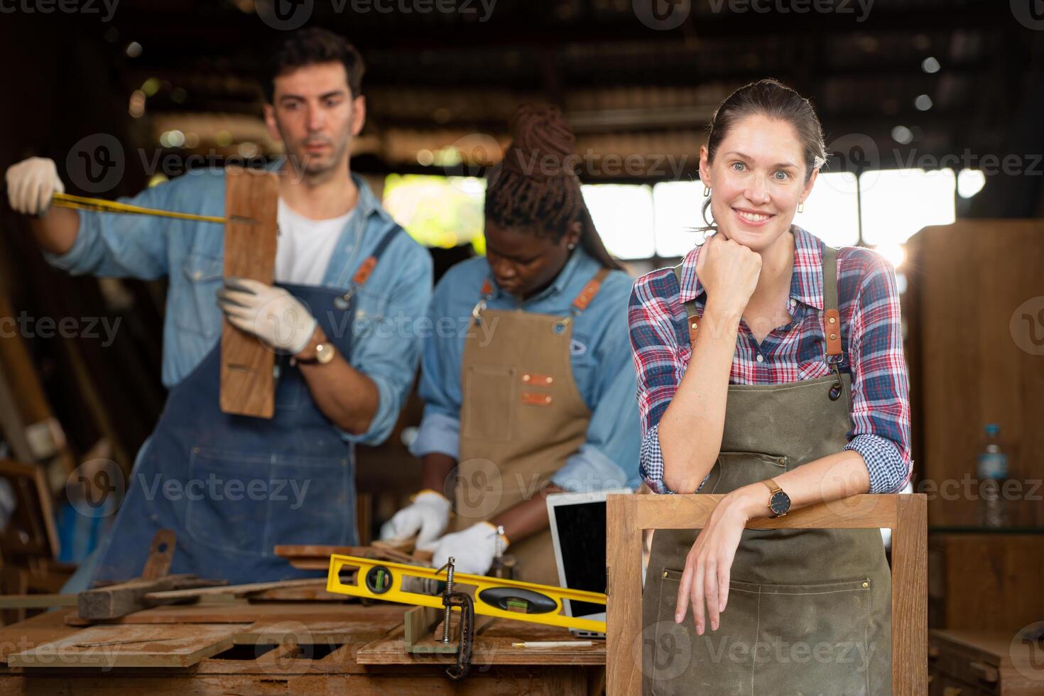 Portrait of carpenter female worker standing in front of colleague in workshop, Eyesight is utilized to ensure accuracy. photo