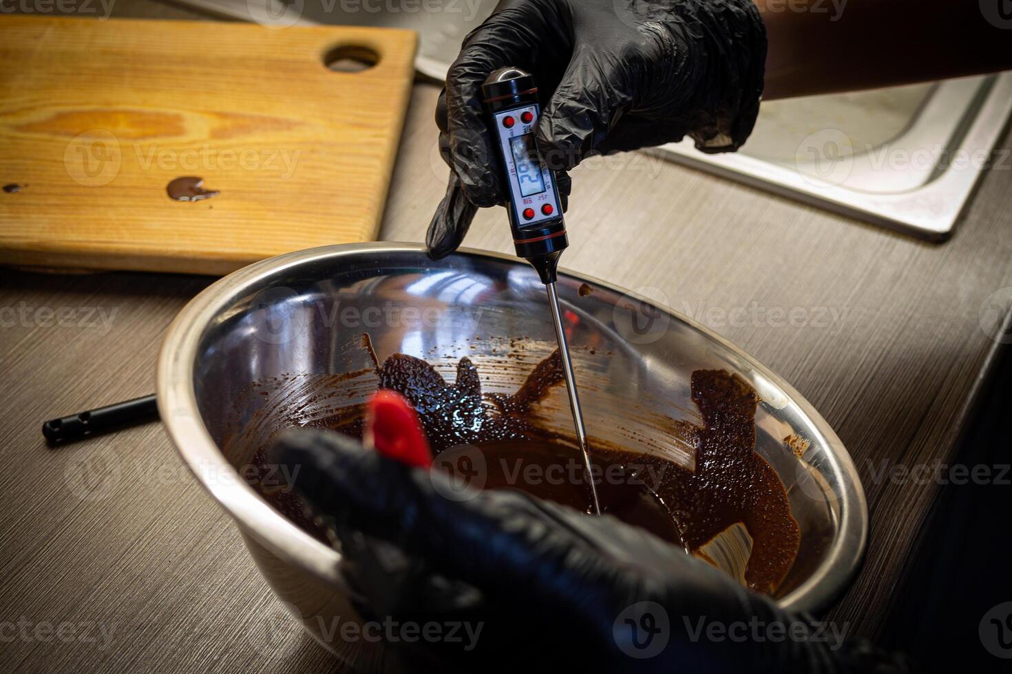 Woman cooking tasty melted chocolate on table in kitchen. photo