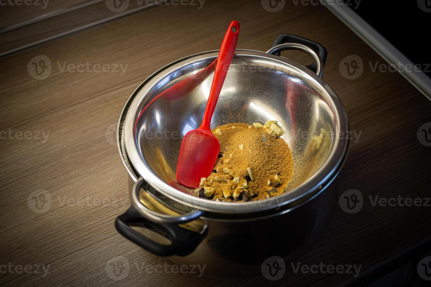 Woman cooking tasty melted chocolate on table in kitchen. photo