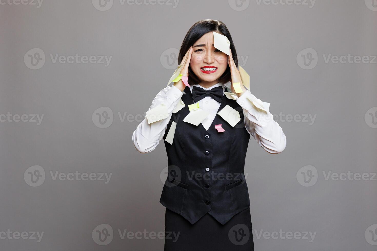 Frustrated asian woman receptionist with sticky notes on face multitasking, panicking and looking at camera. Stressed exhausted busy restaurant waitress overloaded with work portrait photo