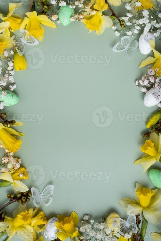 Spring flowers ans easter eggs border on green background with copy space photo