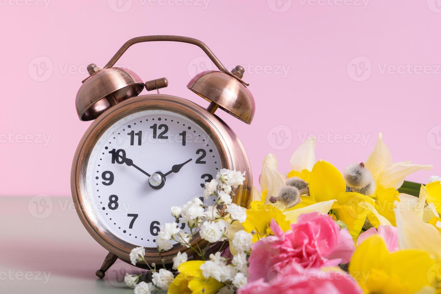 Alarm clock with spring flowers. Spring time, daylight savings concept, spring forward photo