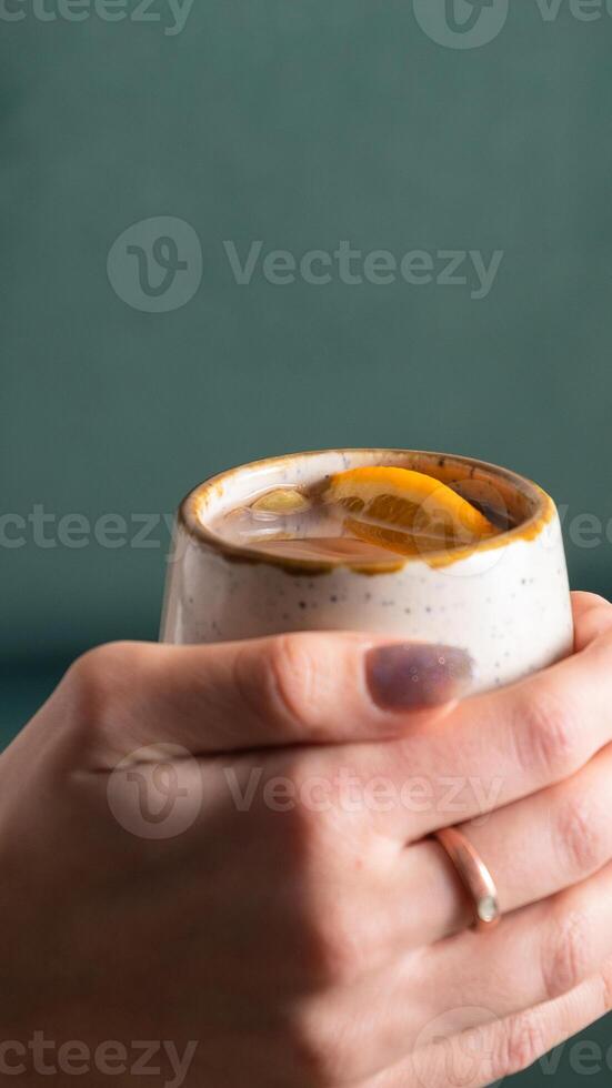 Cup with mulled wine in female hands, angle view. Vertical photo. photo