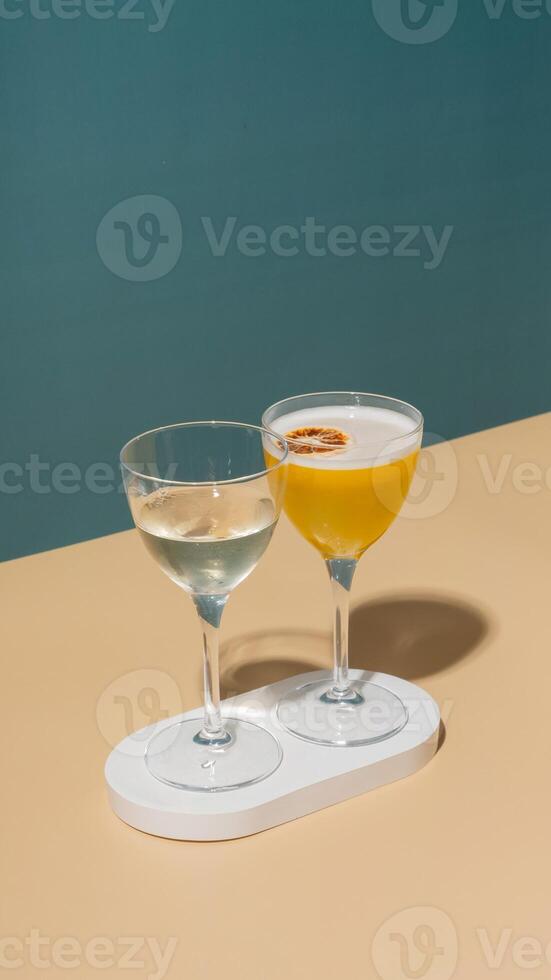 Two glasses with an alcoholic cocktail on a podium on a colored background photo