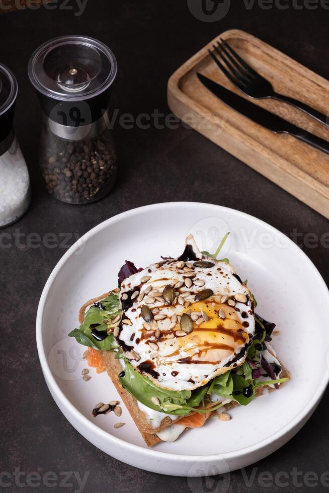 White plate of waffles and salmon with egg and seeds angle view on dark background vertical format. photo