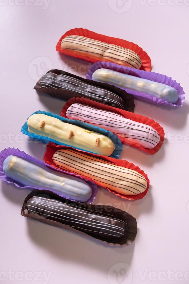 Colored eclairs with different flavors on a colored background. photo