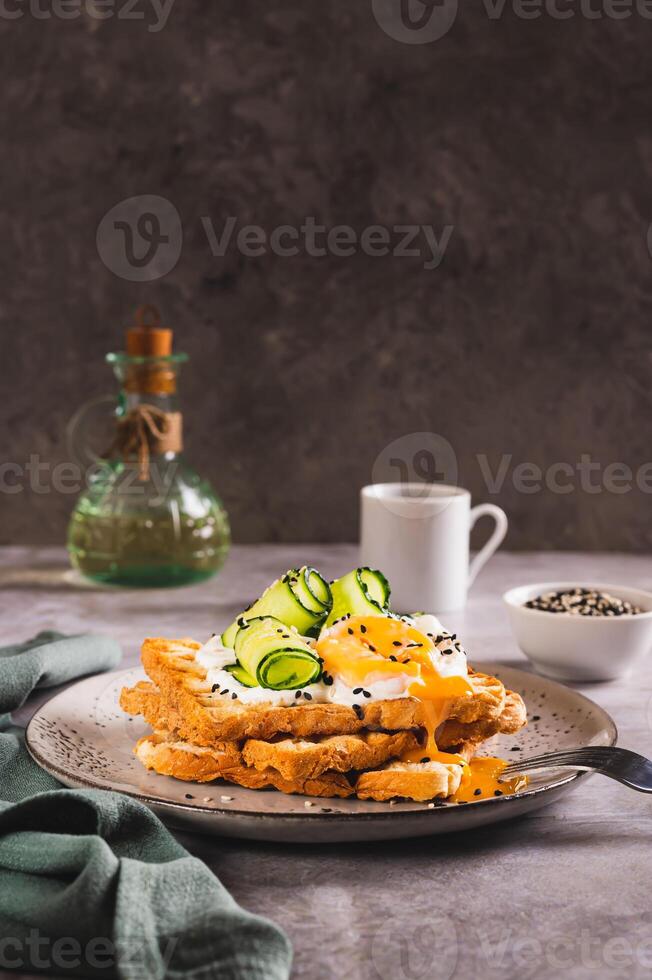 Toasts with cream cheese, cucumber, poached egg and sesame seeds on a plate vertical view photo