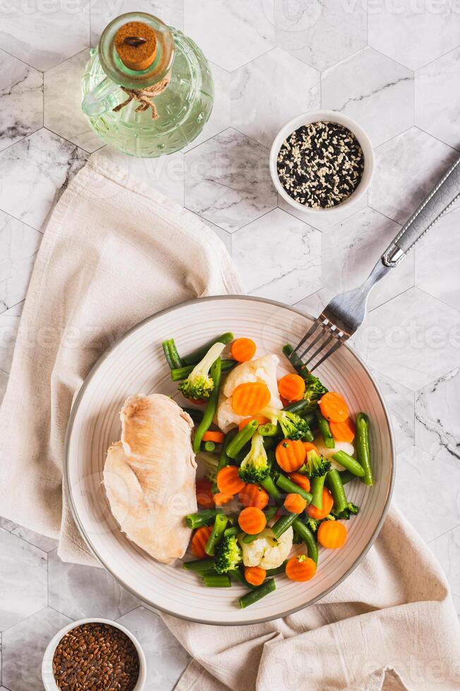 Boiled assorted vegetables and chicken fillet for diet food on a plate top and vertical view photo