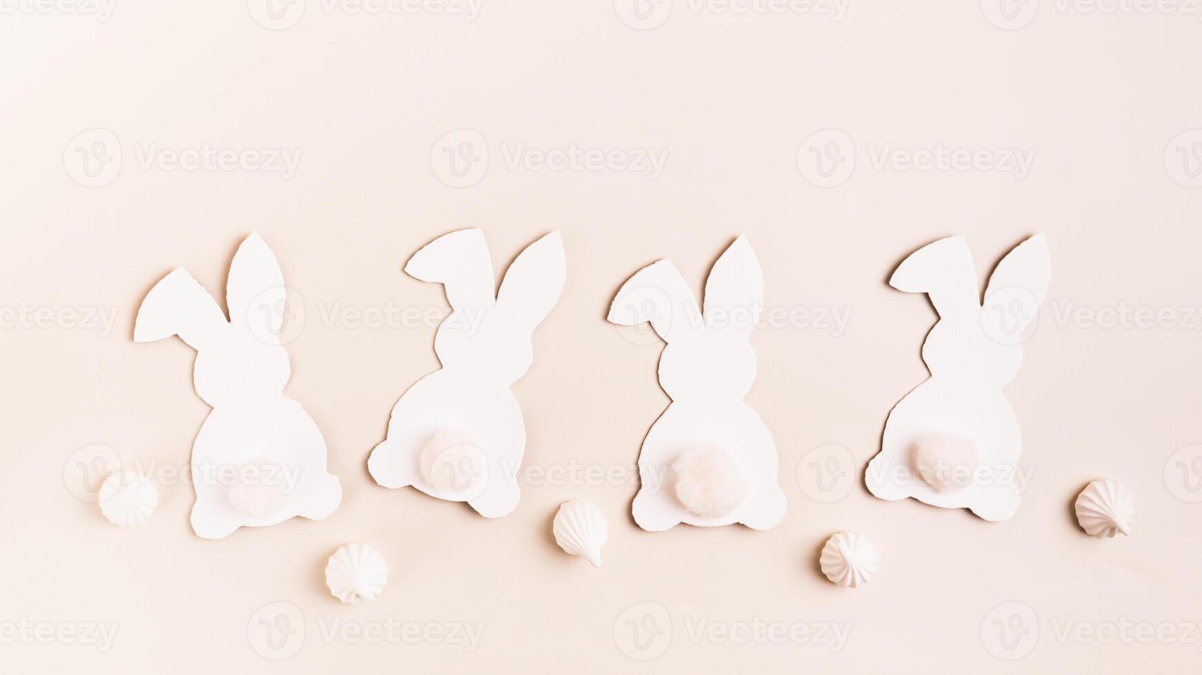 Happy Easter white decorative bunnies and mini meringues on pink background top view web banner photo