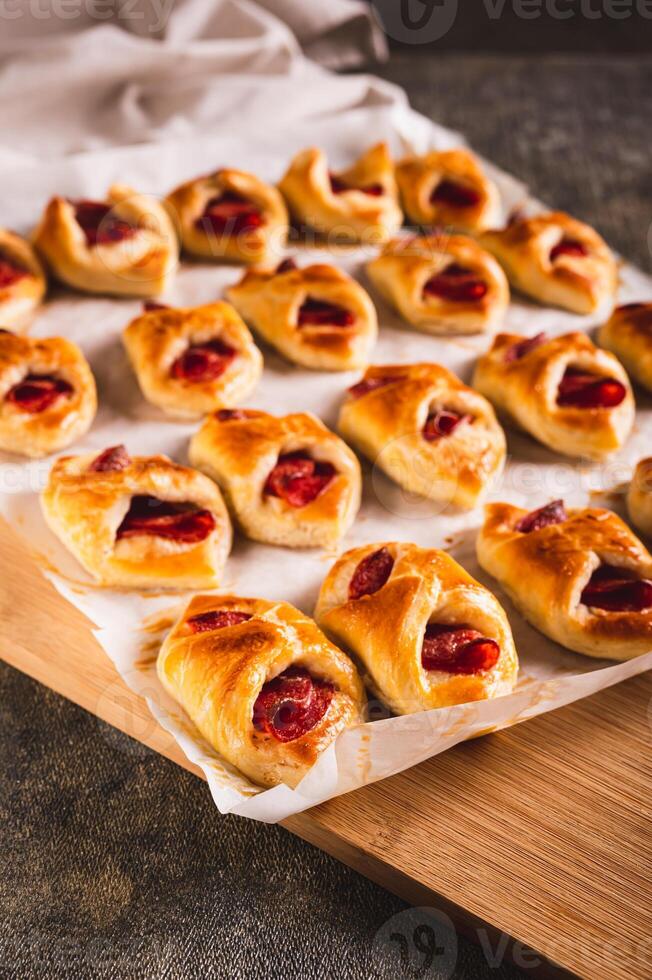Homemade envelopes with cheese and pepperoni sausage on paper on a board vertical view photo