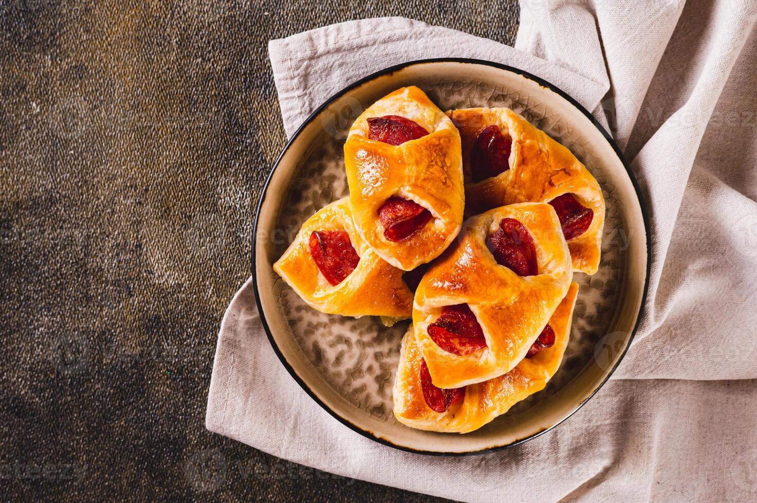 Close up of envelopes with cheese and pepperoni sausage on a plate on the table top view photo