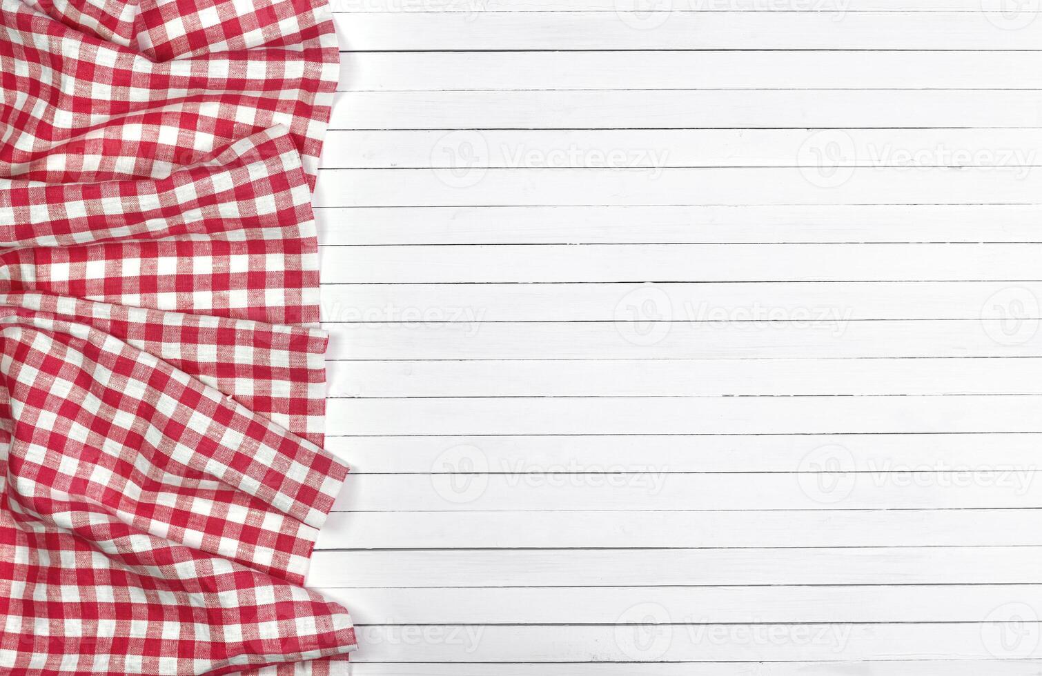 Red tablecloth on white wooden table, top view photo