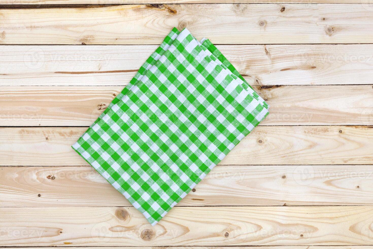 Green tablecloth on wooden table, top view photo