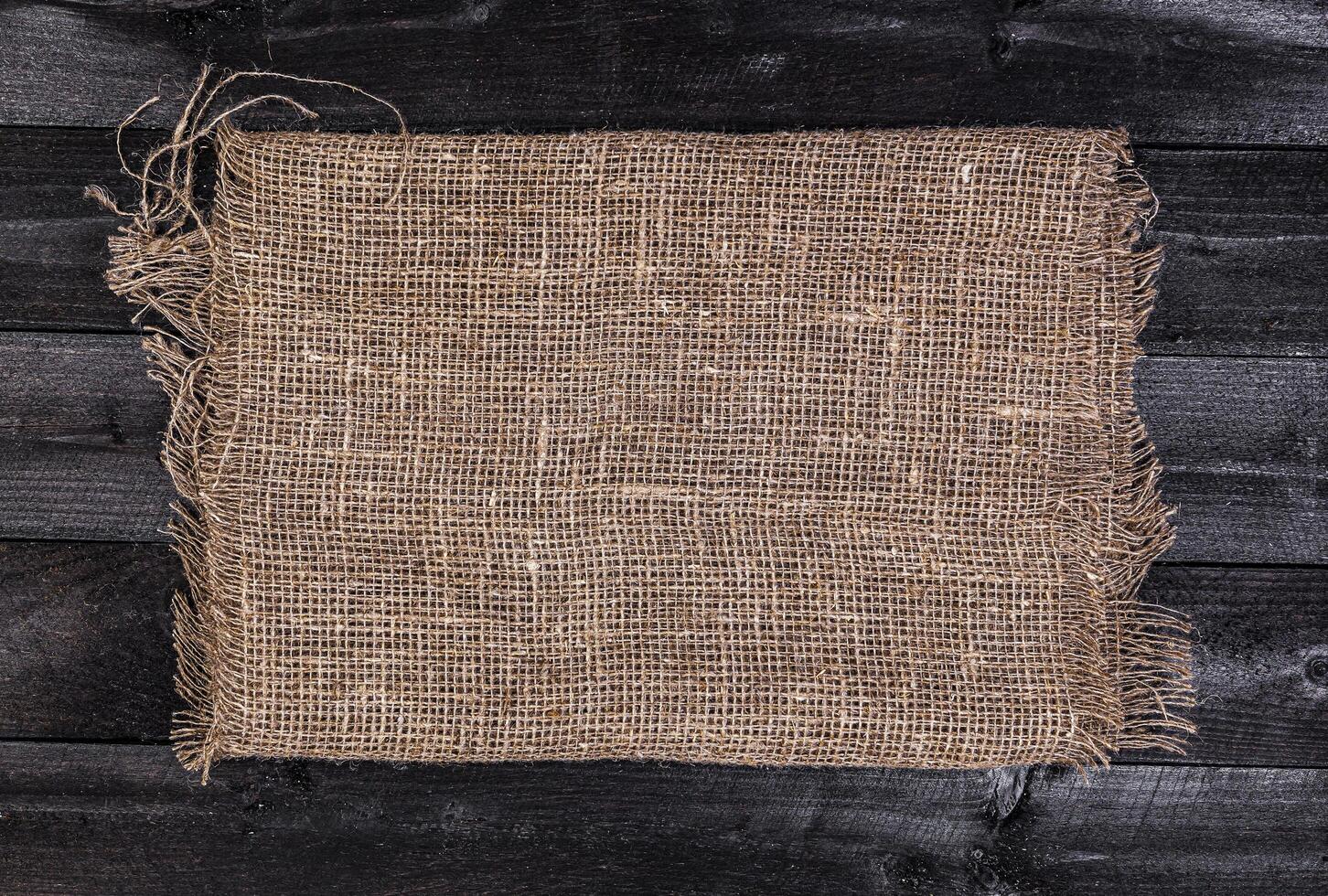 Burlap on black wooden background, top view photo