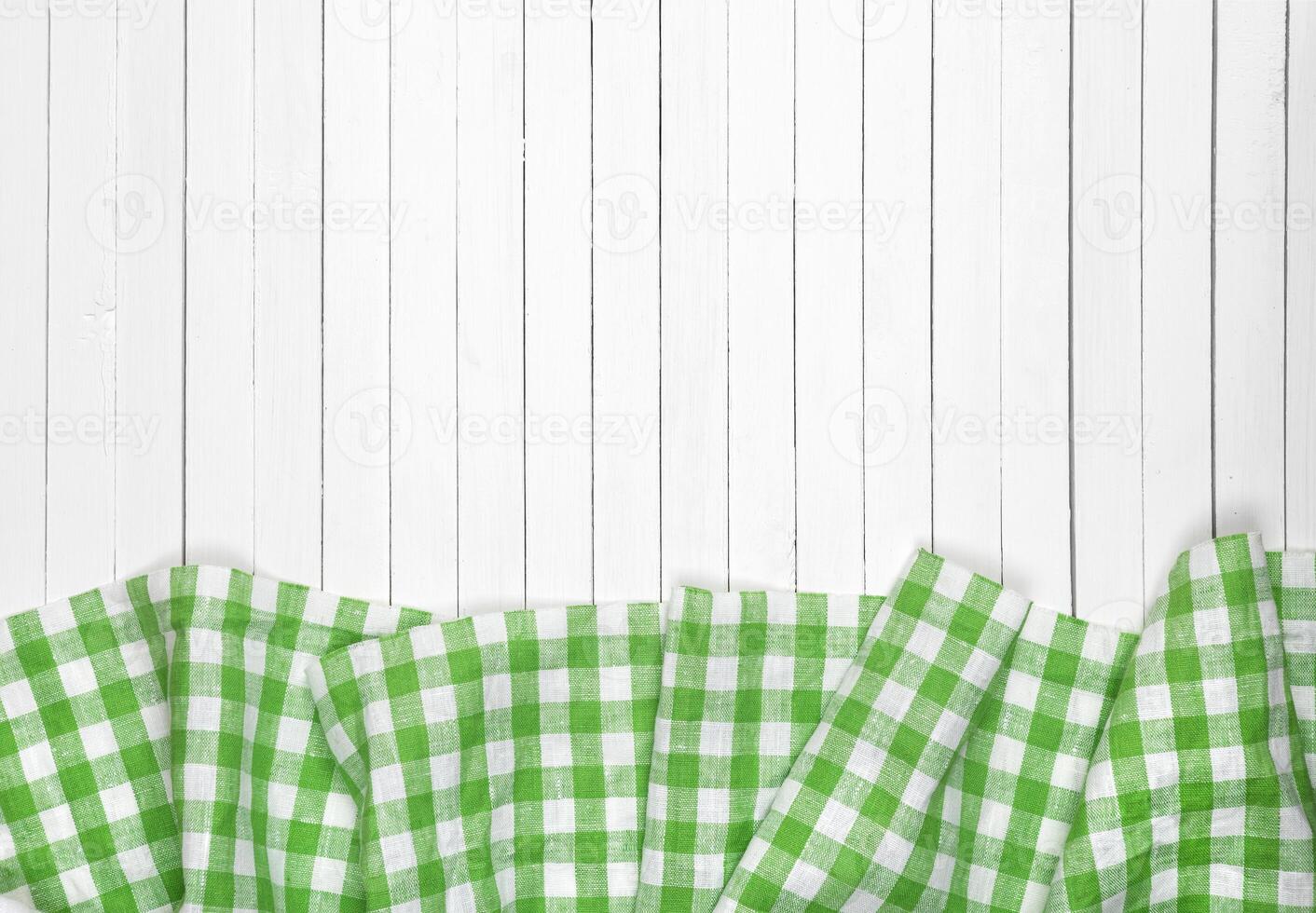 Green checkered tablecloth on wooden table, top view photo