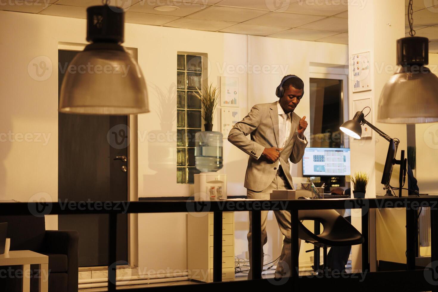 African american employee having fun in startup office, listening music while showing funny dance moves. Executive manager working overhours at company investment plan. Business concept photo