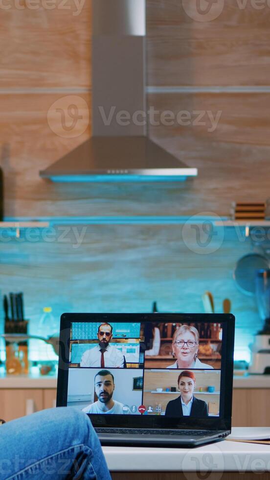 Businesswoman on video conference working remotely from home sitting in the kitchen late at night. Lady using modern technology network wireless talking on virtual meeting at midnight doing overtime photo