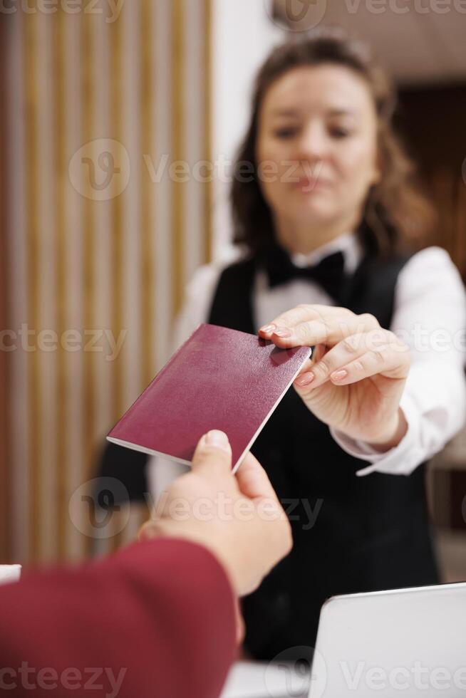 Hotel concierge checks passport, taking identification files from guest to fill in papers and help him settle in. Businessman in suit travelling for corporate work trip. Close up. photo