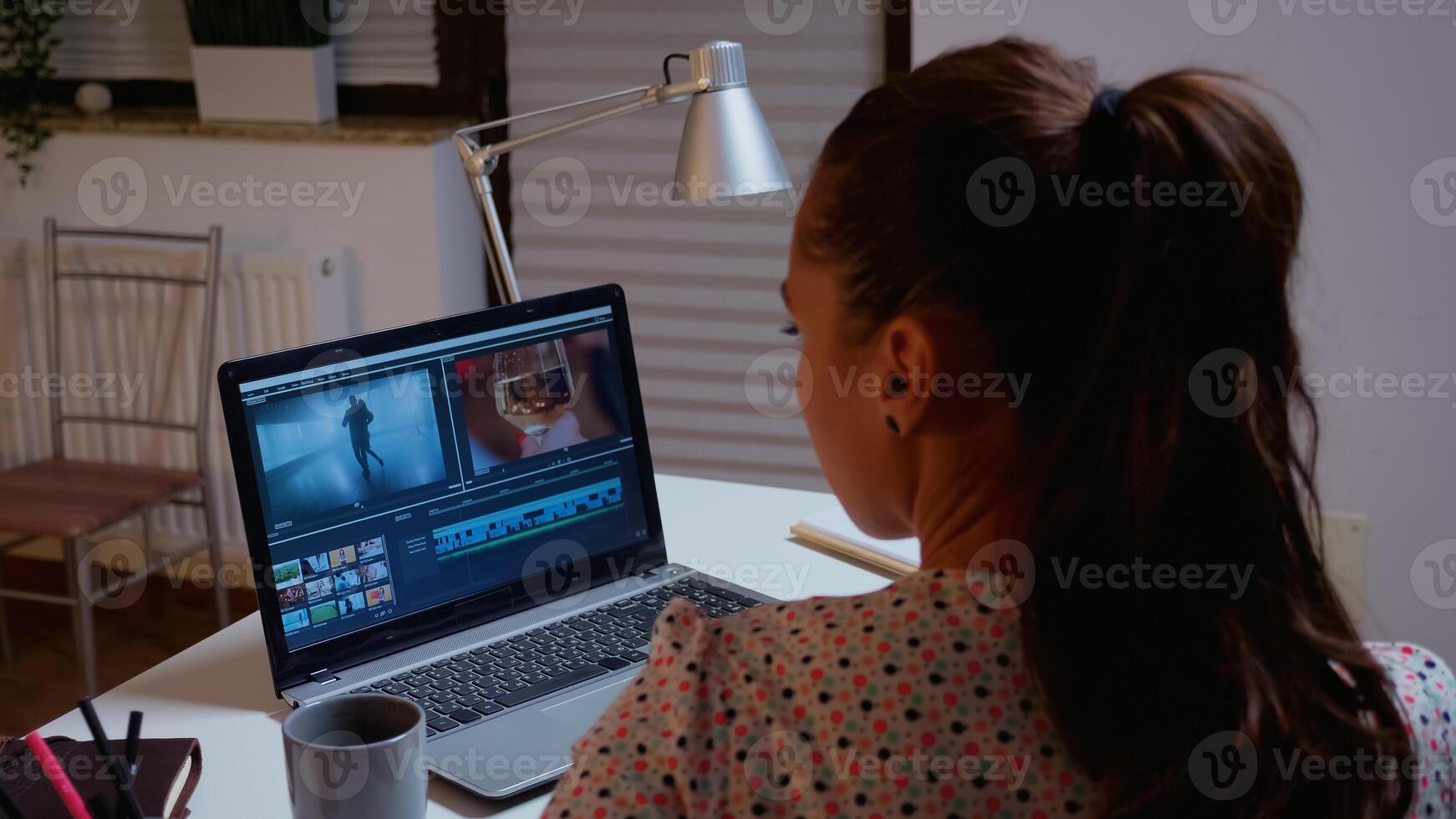 Movie maker editing a film using modern software for post production. Videographer working on audio film montage on professional laptop sitting on desk in modern kitchen in midnight photo