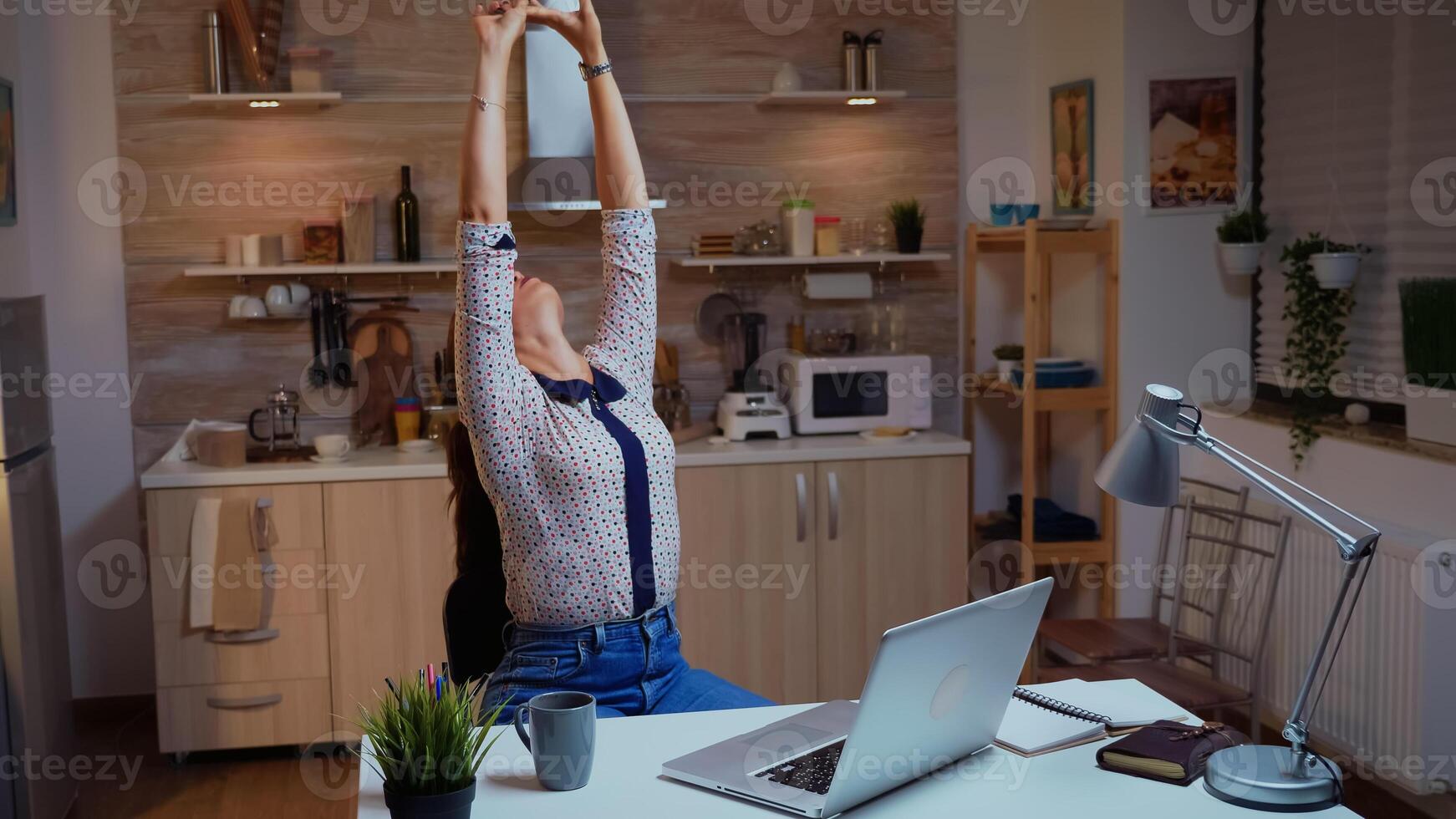 Exhausted remote employee streching while working on a deadline late at night. Busy focused freelancer using modern technology network wireless doing overtime for job reading writing, searching photo