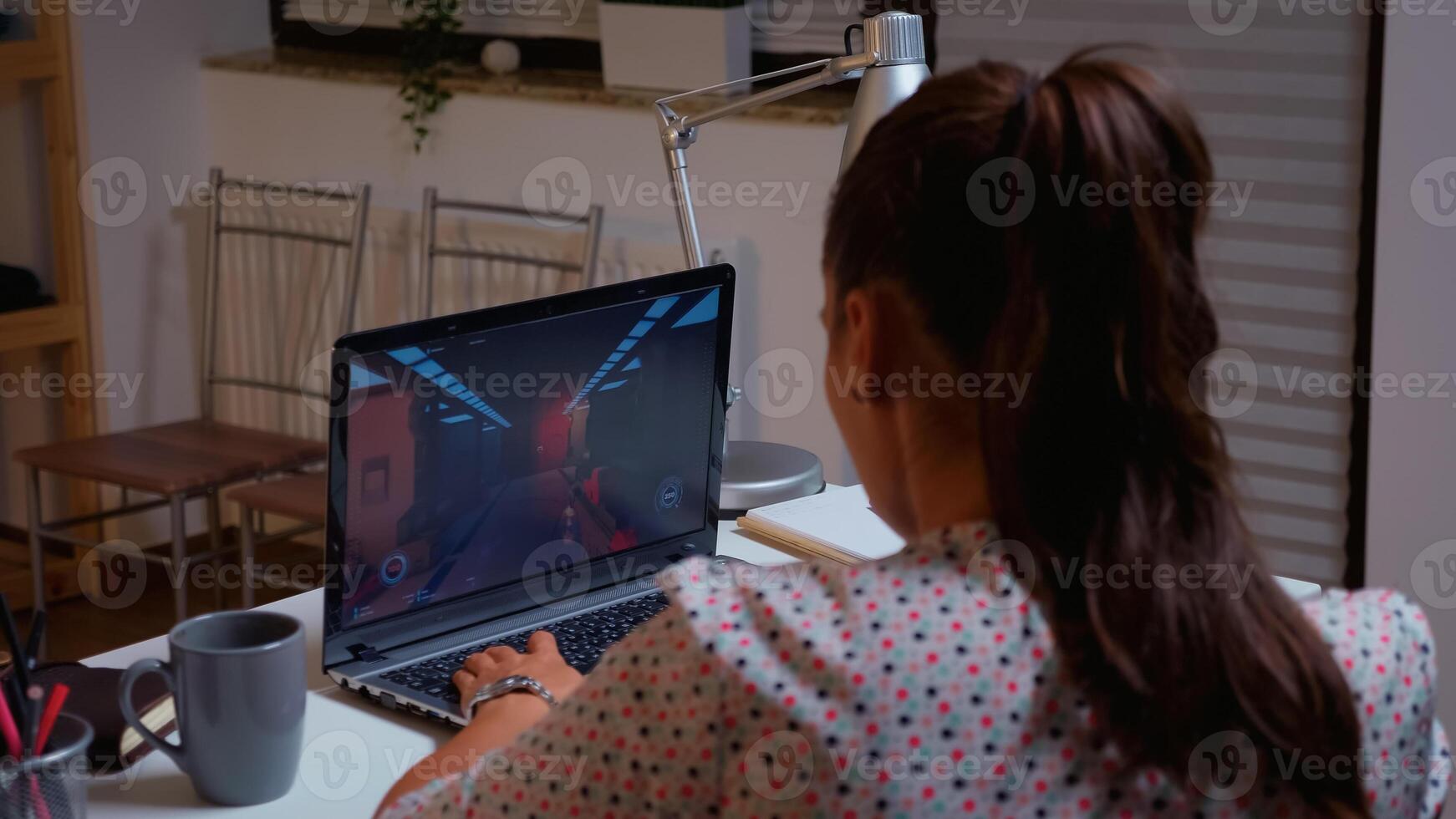 Female gamer playing video game in midnight from home using professional laptop. Professional player testing online video games on her personal computer with modern technology network wireless. photo
